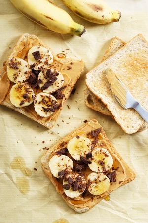 healthy whole wheat toasted bread with peanut butter and sliced bananaの写真素材