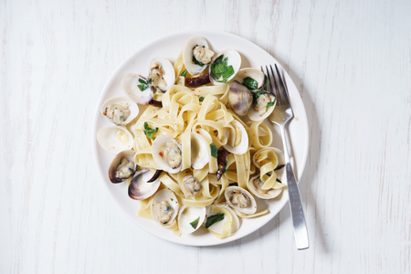 Clam linguine dish, seafood pasta, with pepper and basil on white plateの写真素材