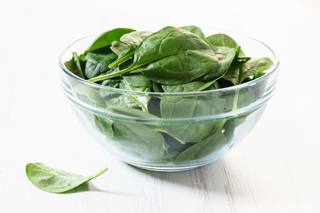 Bowl of fresh spinach on woodenの写真素材