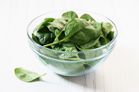 Bowl of fresh spinach on woodenの写真素材