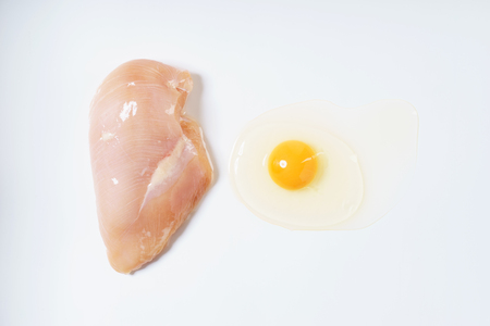 Raw chicken breast fillet and egg on whiteの写真素材