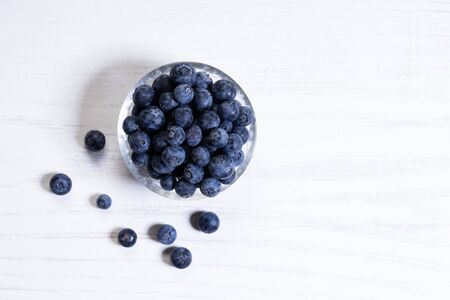 Fresh blueberries in glass bowl on white woodenの写真素材