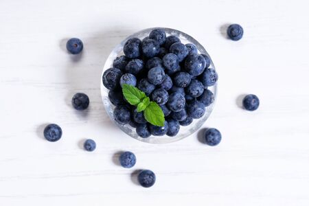 Fresh blueberries in glass bowl on white woodenの写真素材