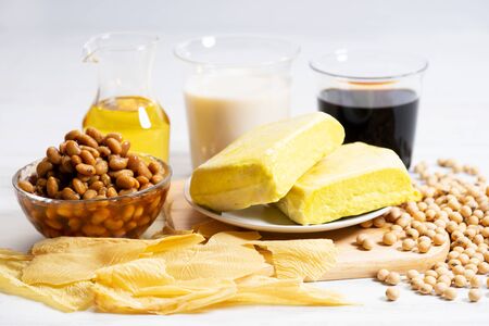 Soy products with soy milk, tofu, soy sauce, soy oil, soy paste and dried bean curd on white wooden backgroundの写真素材