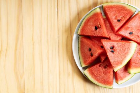 Fresh watermelon slices in white plate on wooden backgroundの写真素材