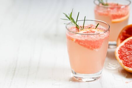 Fresh grapefruit cocktail with fresh rosemary on white wooden table, with copy spaceの写真素材