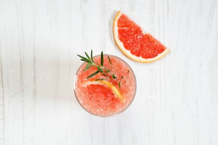 Fresh grapefruit cocktail with fresh rosemary on white wooden table, top viewの写真素材