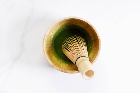 Green tea, matcha, in wooden bowl with bamboo whisk. top view