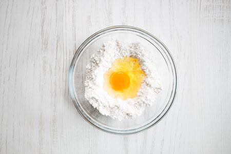 Bakery ingredients on white wooden table. egg and flour ina glass bowlの写真素材