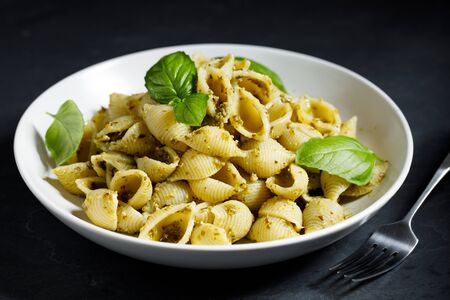 Conchiglie pasta with pesto sauce on dark background, vegan dishの写真素材