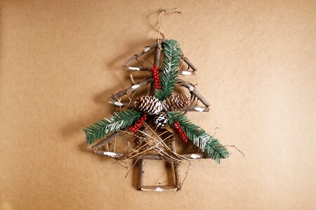 Christmas decorations in Christmas tree shaped with pine cone and holly on brown background. Top view.の写真素材