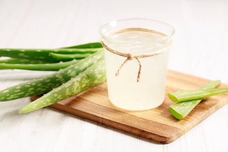 Healthy aloe vera juice in a glass with fresh aloe vara leaves on wooden paddle boardの写真素材