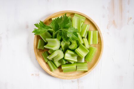 sliced of fresh celery stalk with leaves on white wooden backgroundの写真素材