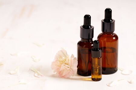 amber glass bottles with glass droppers on white wooden table with natural productsの写真素材