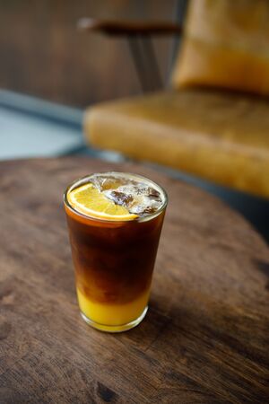 glass of iced coffee with orange juice on wooden tableの写真素材