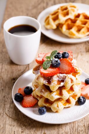homemade waffles with syrup and fresh berries on wooden tableの写真素材