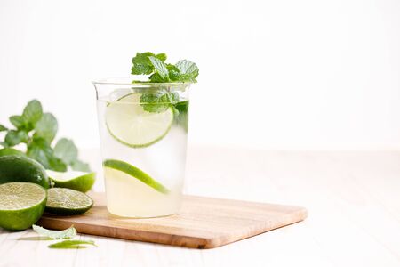 Lemonade or mojito cocktail with fresh lime and mint leaves, cold refreshing drink with ice on wooden table.の写真素材