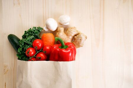 Fresh vegetables in paper bag on light wooden background. Food bag and eco-friendly concept. Healthy food background.の写真素材