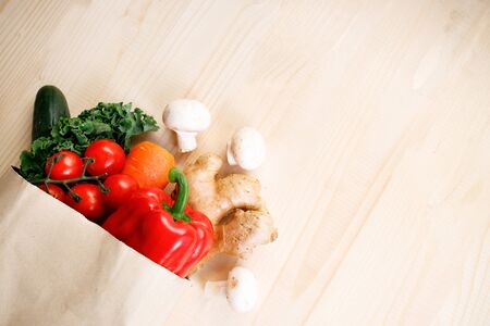 Fresh vegetables in paper bag on light wooden background. Food bag and eco-friendly concept. Healthy food background.の写真素材