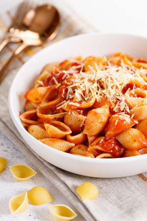 Pasta conchiglie with tomato sauce and parmesan cheese in white dish, simple meal conceptの写真素材