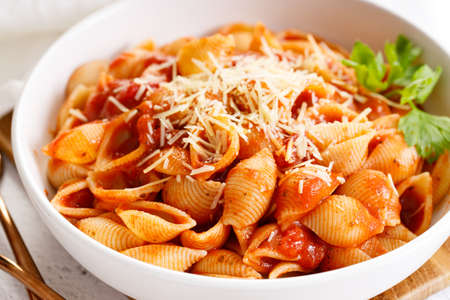 Pasta conchiglie with tomato sauce and parmesan cheese in white dish, simple meal conceptの写真素材