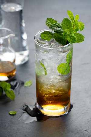 mojito cocktail, cold drink with ice cubes and fresh mint leaves on rustic dark table.の写真素材