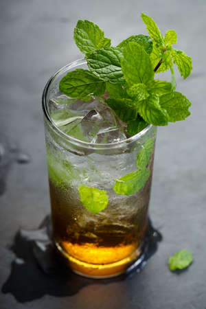 mojito cocktail, cold drink with ice cubes and fresh mint leaves on rustic dark table.の写真素材