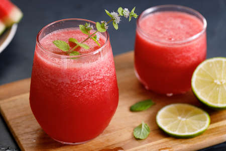 Glass of healthy watermelon smoothie with mint leaves on dark backgroundの写真素材