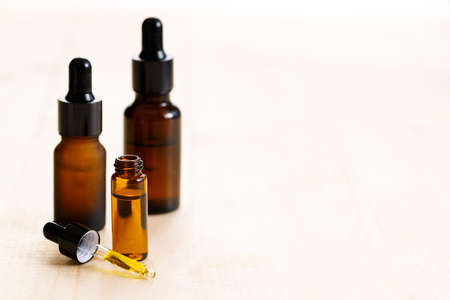 Essential oil in amber glass bottle with fresh green mint leaves on wooden background, with copy space.の写真素材