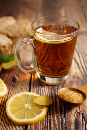 Lemon ginner tea with sliced fresh lemon and honey sugar on dark wooden tableの写真素材