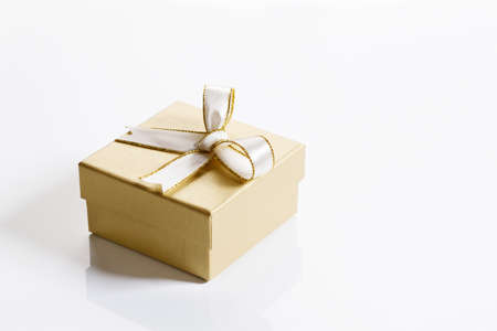 golden color present box with white ribbon bow on white background