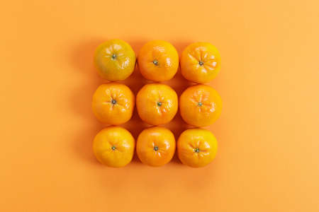 fresh oranges, on orange color paper background, arrange in square pattern. top view.の写真素材