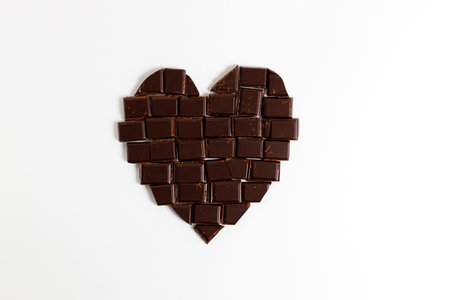 Chocolate pieces arrange in heart shape on white background, top view.の写真素材