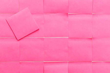 Sticky note in pink color as background, top viewの写真素材