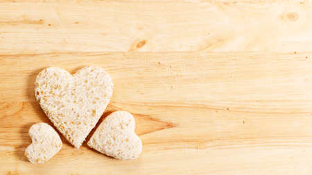 wholewheat bread cut into heart shape on wooden background, top viewの写真素材