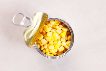 Open tin can of yellow corn on kitchen table background. top view.の写真素材