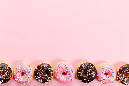donuts with chocolate frosted, pink glazed and sprinkles on pink background.の写真素材