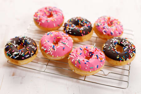 donuts with chocolate frosted, pink glazed and sprinkles on baking rack.の写真素材