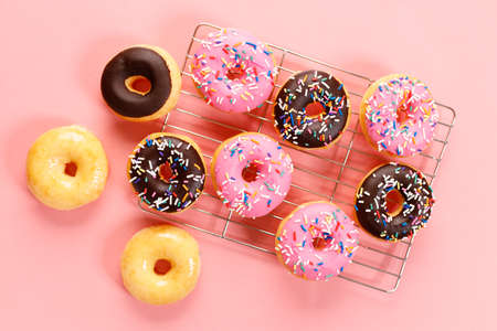 donuts with chocolate frosted, pink glazed and sprinkles on pink background.の写真素材