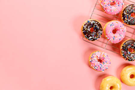 donuts with chocolate frosted, pink glazed and sprinkles on pink background.の写真素材