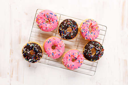 donuts with chocolate frosted, pink glazed and sprinkles on baking rack. top view.の写真素材