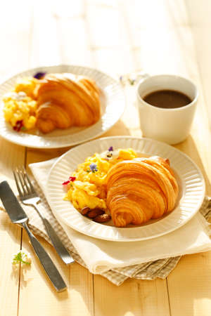 croissants with scrambled egg and cup of hot chocolate on wooden table. Breakfast concept.の写真素材