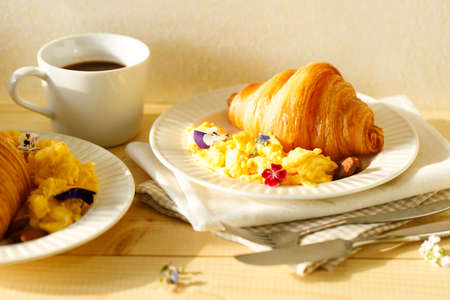 croissants with scrambled egg and cup of hot chocolate on wooden table. Breakfast concept.の写真素材