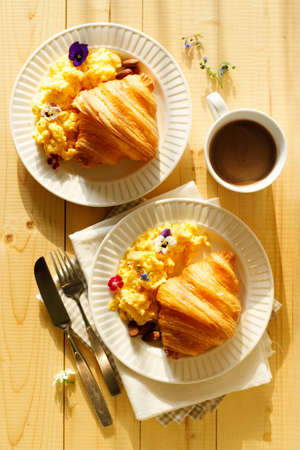 croissants with scrambled egg and cup of hot chocolate on wooden table. Breakfast concept.の写真素材