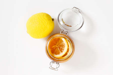Homemade honey lemon preserve in a glass jar with fresh lemon and honey on white stone table. healthy lifestyle.の写真素材
