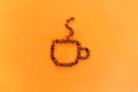 roasted coffee beans on a orange color paper background with abstract shape, topview.の写真素材