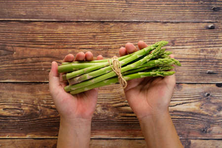 Bunch of fresh green asparagus in handの写真素材