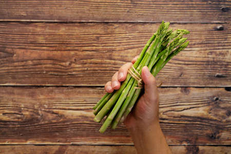 Bunch of fresh green asparagus in handの写真素材