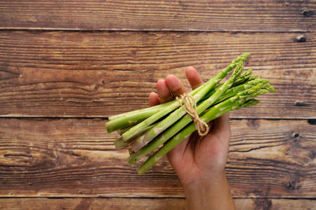 Bunch of fresh green asparagus in handの写真素材
