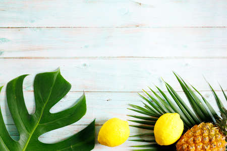 Tropical leaves monstera with fruits on a wooden table background. Top view. Minimal summer background.の写真素材